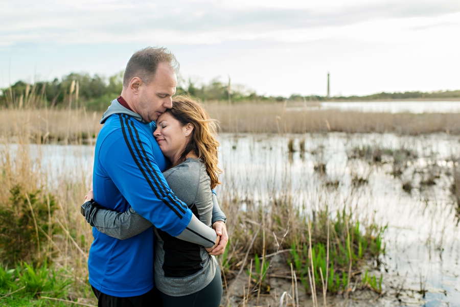 A woman rests her head in her fiance's chest by the beach of Cape May, NJ during their engagement session.